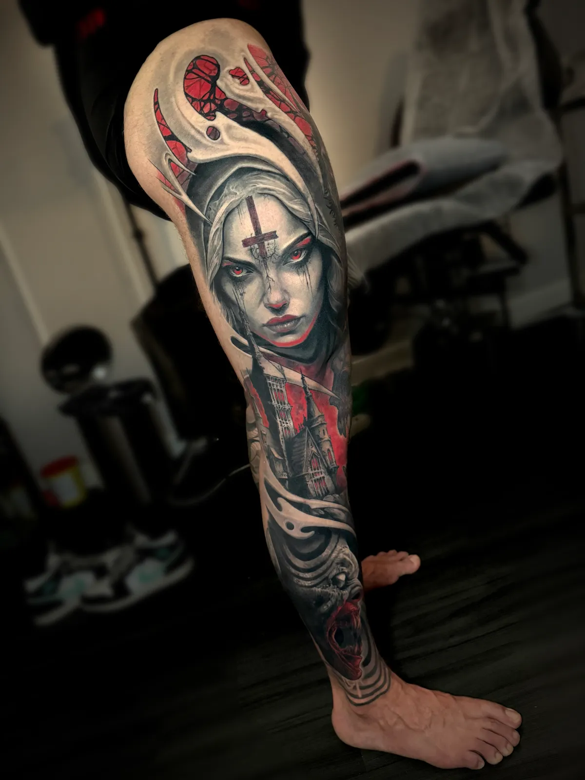 Dark art full leg sleeve tattoo with gothic nun portrait, red accent highlights and cathedral by Paul Michael Andras